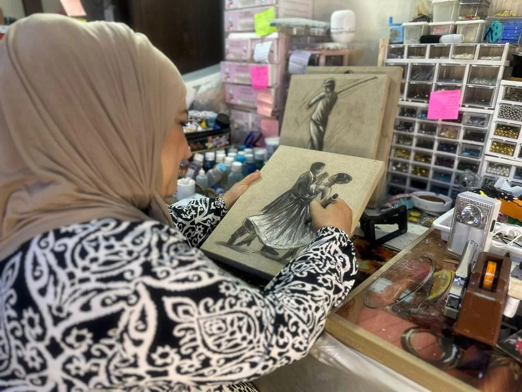 Diyala, 2026: Suad paints on a piece of old used fabric. KirkukNow